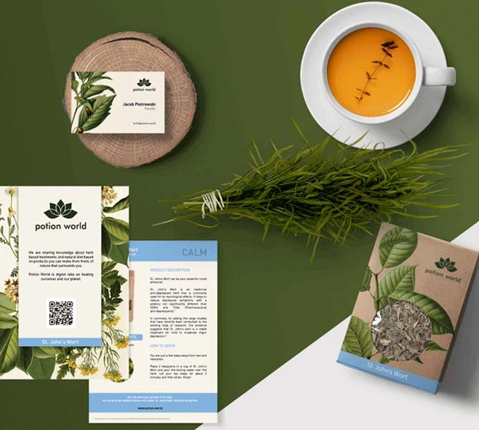 A cup of tea beside a card and leafy greenery.